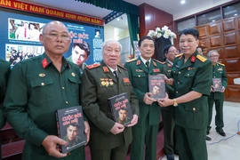 Đại tá Đặng Vương Hưng tặng tác phẩm “Cuộc đời còn mãi” cho các cựu chiến binh. (Ảnh: PV/Vietnam+)