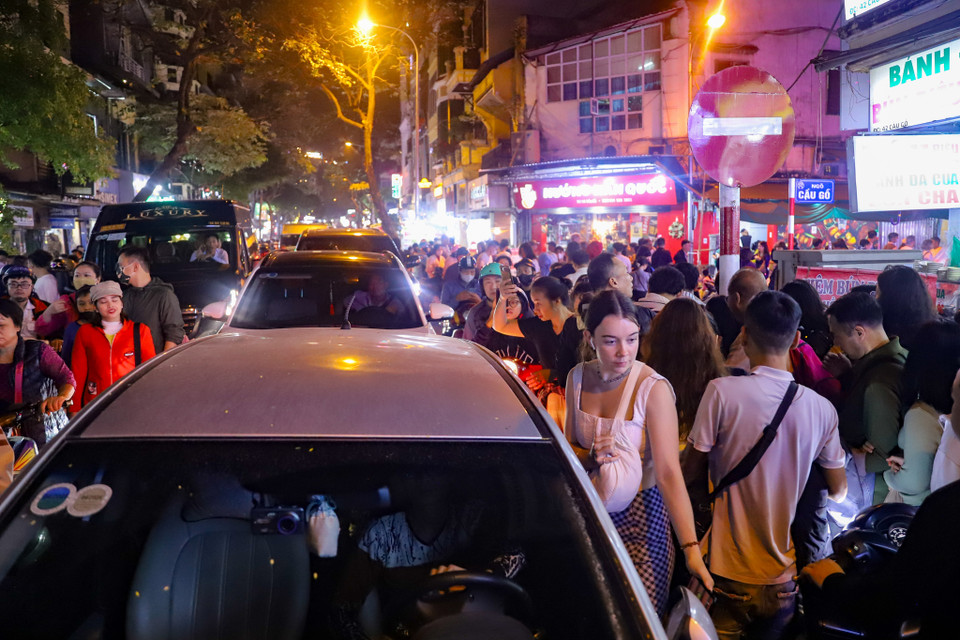 Càng về khuya, dòng người càng đông đúc trên tuyến phố Cầu Gỗ để di chuyển về không gian tổ chức sự kiện đếm ngược tại Quảng trường Đông Kinh Nghĩa Thục. (Ảnh: Hoài Nam/Vietnam+)