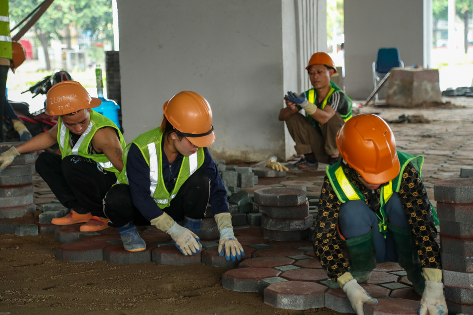 Các công nhân đang hoàn thiện việc lát gạch dưới chân gầm cầu vượt. (Ảnh: PV/Vietnam+)