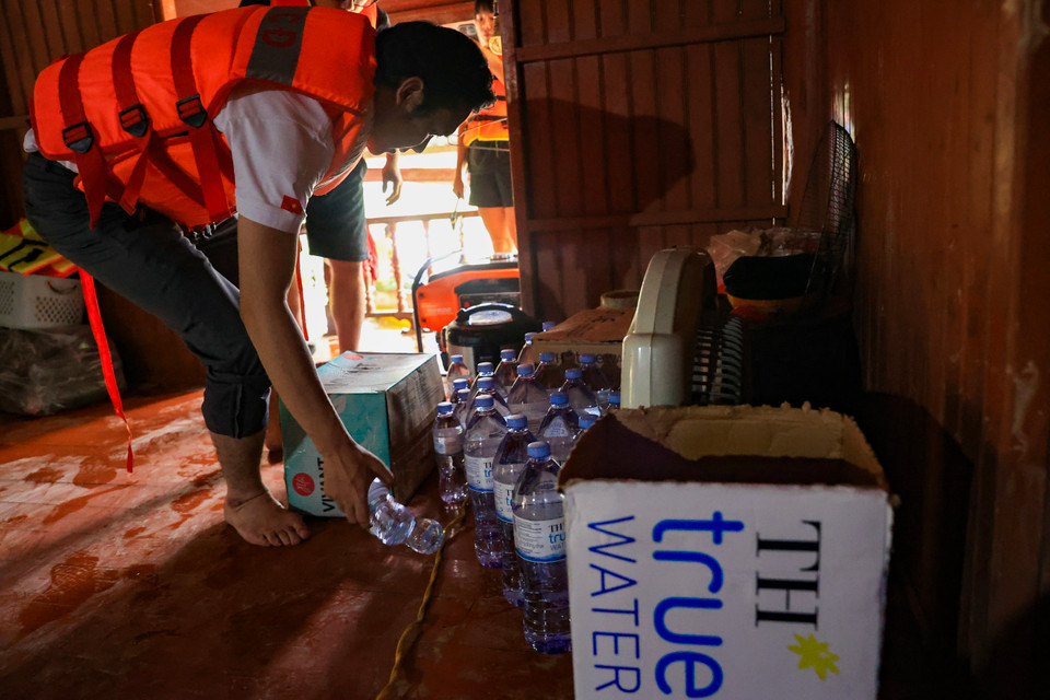 Nguồn nước lũ nhiễm bẩn khiến vi khuẩn, virus và ký sinh trùng có điều kiện sinh sôi, dẫn đến lan truyền mầm bệnh. Do đó, những chai nước tinh khiết lúc này vô cùng quý giá. (Ảnh: Hoài Nam/Vietnam+)