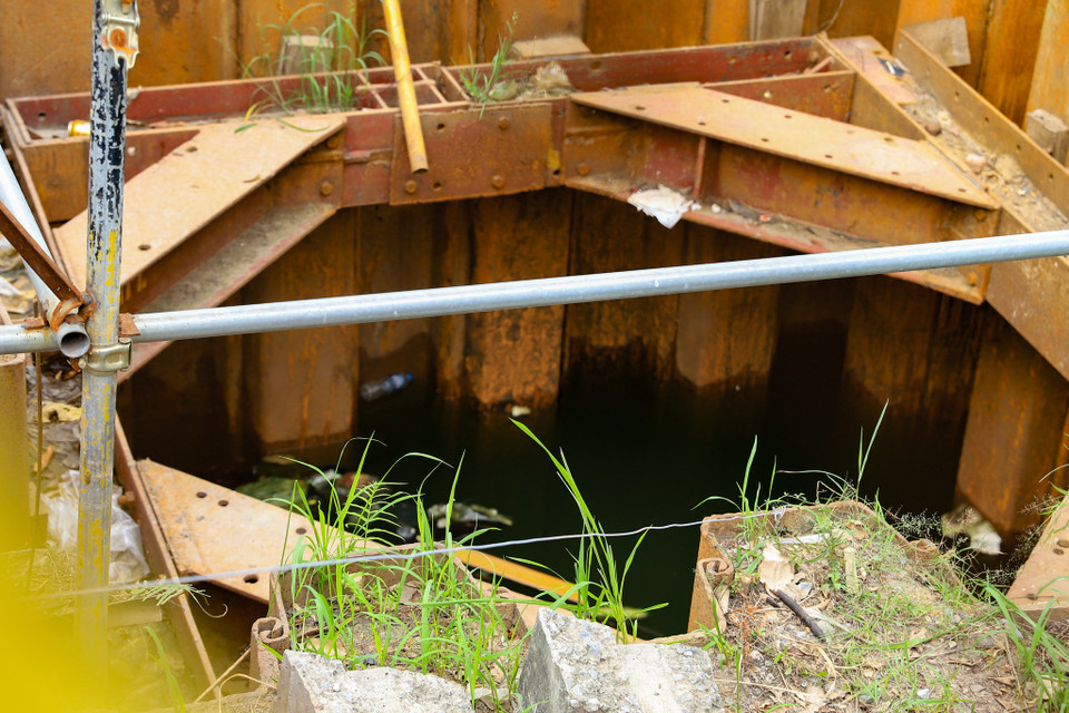 Cỏ dại mọc bên cạnh giếng nước đen ngòm cùng các hạng mục kim loại đã hoen gỉ. (Ảnh: Hoài Nam/Vietnam+) 