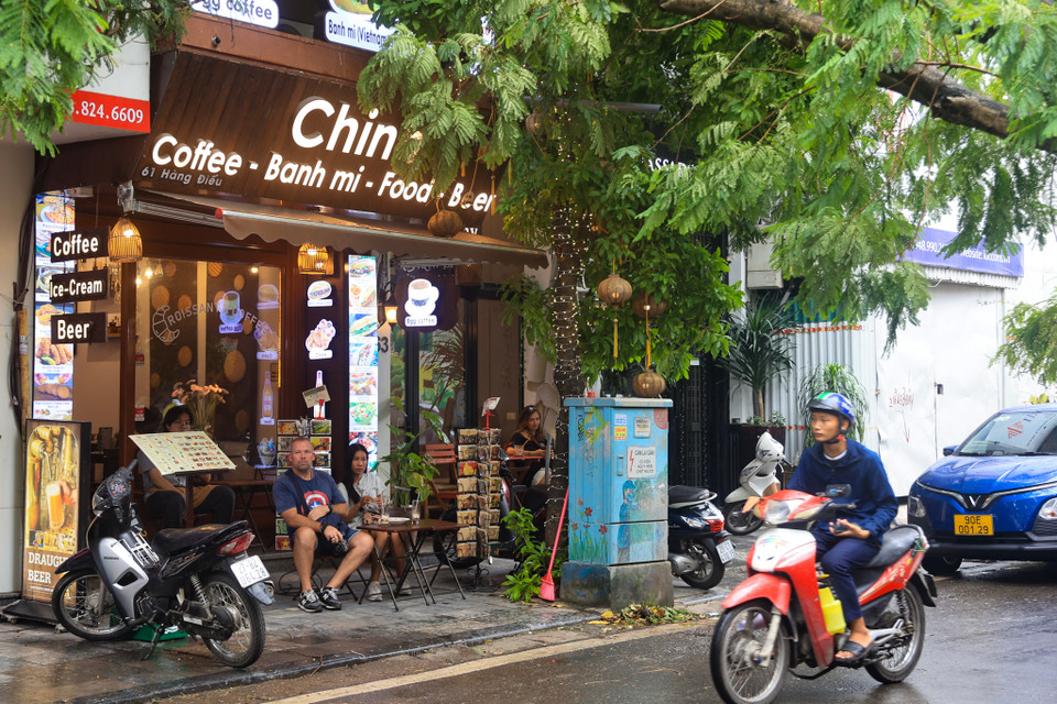 Một cơ sở kinh doanh dịch vụ tại số 61 Hàng Điếu (Cửa Đông, Hoàn Kiếm, Hà Nội) vẫn bày bàn ghế ra vỉa hè cho du khách nước ngoài ngồi dưới cây đang đổ. (Ảnh: Hoài Nam/Vietnam+)