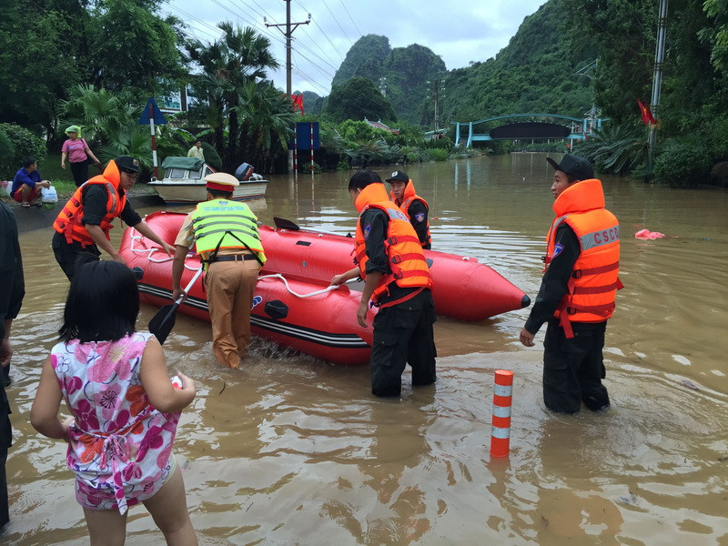 Các chiến sĩ công an giúp dân di chuyển an toàn qua chỗ ngập sâu (Ảnh: Nguyễn Hoàng/TTXVN)