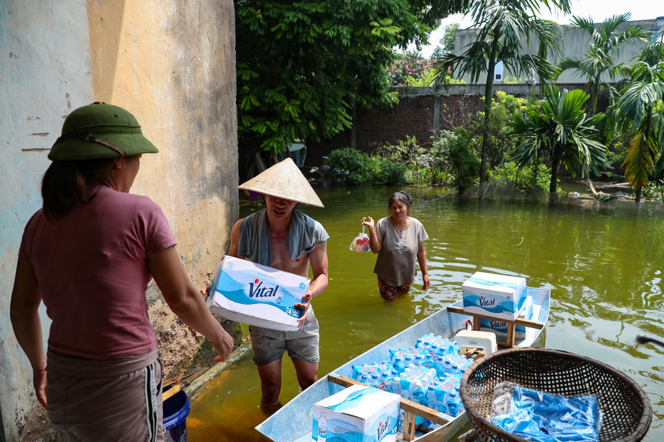 Chính quyền cùng các mạnh thường quân vẫn hằng ngày tiếp nước, tiếp sức cho bà con trong cơn lũ. (Ảnh: Hoài Nam/Vietnam+)