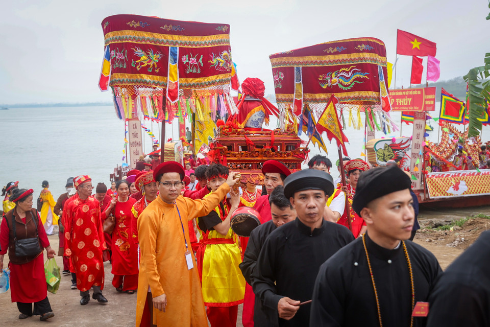 Hoàn thành nghi thức lấy nước, đoàn rước lại trở về Đền thờ các vị vua Trần. Về tới sân Đền, đoàn rước lần lượt đi vào hành lễ, đoàn kiệu do các thanh niên trai tráng rước qua cổng là bắt đầu quay đủ ba vòng rồi đi vòng vào Đền. (Ảnh: Hoài Nam/Vietnam+)