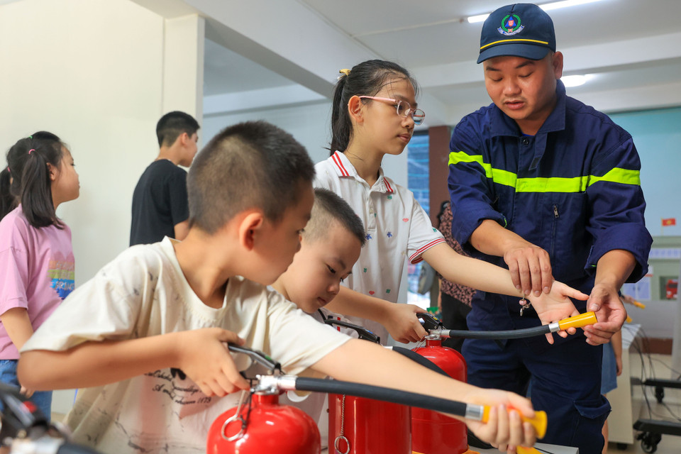 Cán bộ chiến sỹ Phòng cảnh sát phòng cháy chữa cháy và cứu nạn cứu hộ Công an thành phố Hà Nội hướng dẫn các em nhỏ sử dụng bình cứu hỏa tại khu trải nghiệm thực tế ảo. (Ảnh: Hoài Nam/Vietnam+)