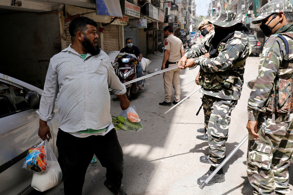 Một người ra ngoài mua thực phẩm bị cảnh sát vụt thẳng tay (Nguồn: Reuters)