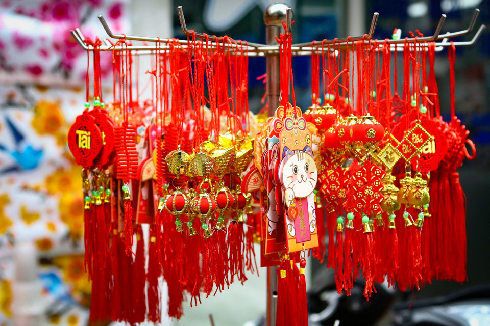 Câu đối, lời chúc,... cũng được nhiều gia đình tìm mua để treo lên cành đào, cây quất. Giá bán dao động từ 50.000 - 120.000 đồng/sản phẩm tùy kích thước. (Ảnh: Hoài Nam/Vietnam+)