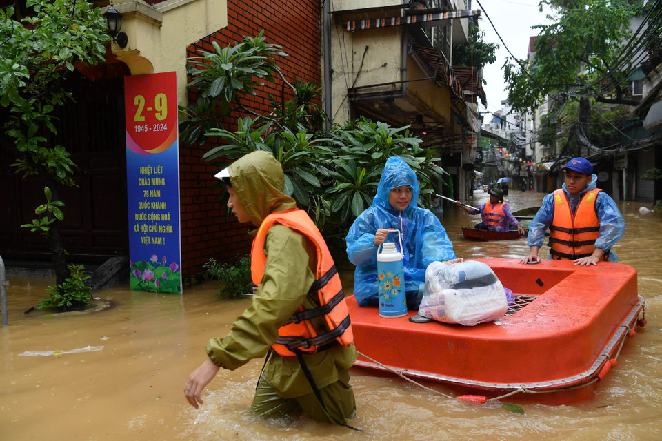 Người dân mang theo những vật dụng sinh hoạt tạm thời sơ tán đến nơi không bị ngập nước. (Ảnh: PV/Vietnam+)