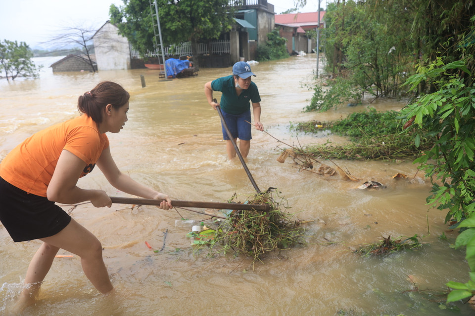 Người dân dọn rác khơi thông dòng chảy để rác không tích tụ tràn vào nhà. (Ảnh: Hoài Nam/Vietnam+)