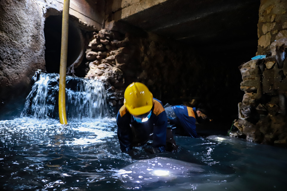 Bên trong ‘thế giới ngầm’ cách mặt đường gần 3m, đội thi công nạo vét trong không khí ngột ngạt và nặng mùi bởi nước thải. (Ảnh: Hoài Nam/Vietnam+)