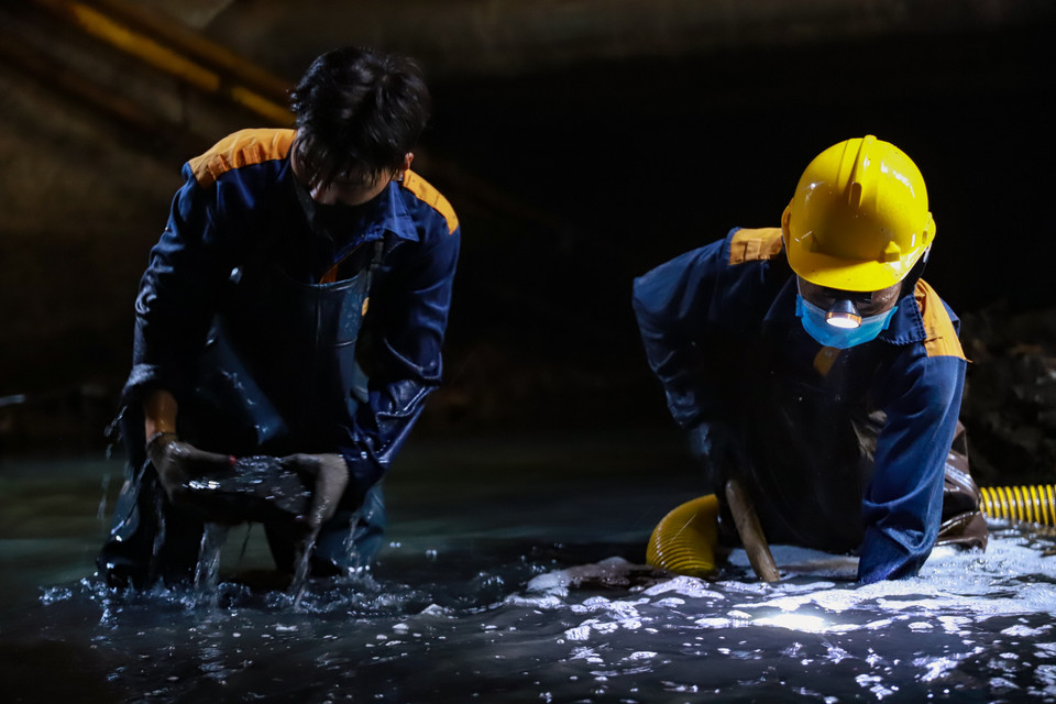 Anh Trị (bên phải) gắn bó với nghề đặc biệt này hơn chục năm nay cùng Hiếu ‘lính mới’ năm nay mới 24 tuổi, vào nghề được hơn 2 tháng bắt đầu thực hiện công việc của mình. (Ảnh: Hoài Nam/Vietnam+)