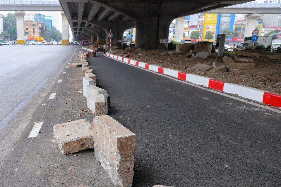 Làn mở rộng trên đường Nguyễn Xiển đã láng nhựa và có thể lưu thông nhưng xe vẫn chưa thể chạy do 2 đầu đường đang bị chặn ngang bởi các trụ, ụ bê tông. (Ảnh: Hoài Nam/Vietnam+)