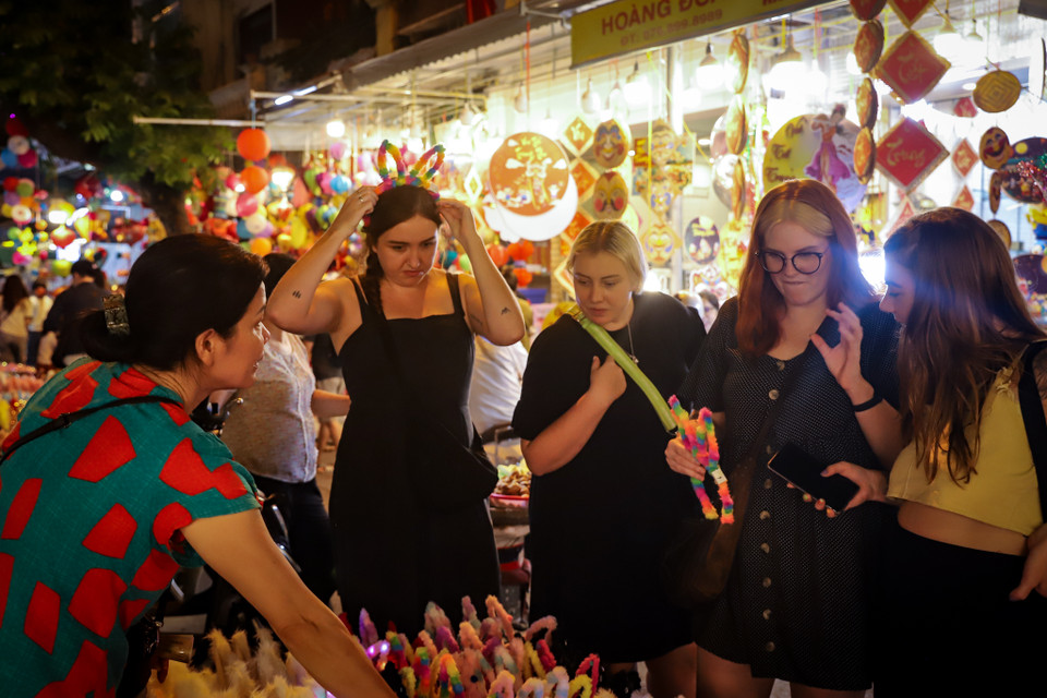 Nhóm du khách nước ngoài thích thú trải nghiệm các món đồ chơi và tận hưởng không khí Tết Trung thu tại Việt Nam. (Ảnh: Hoài Nam/Vietnam+)