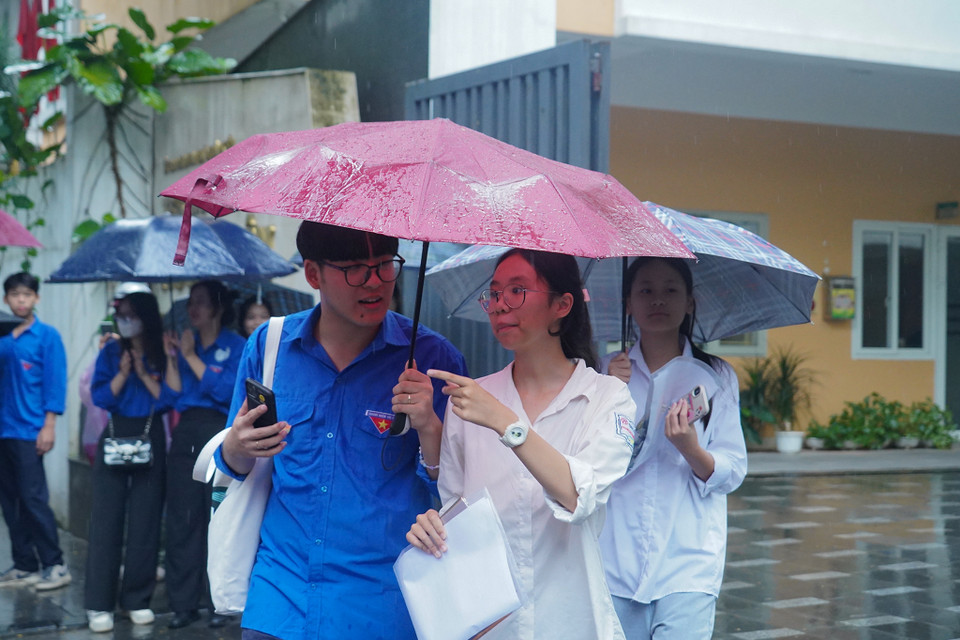 Lực lượng thanh niên tình nguyện hỗ trợ các thí sinh rời điểm thi do trời vẫn mưa. (Ảnh: PV/Vietnam+)