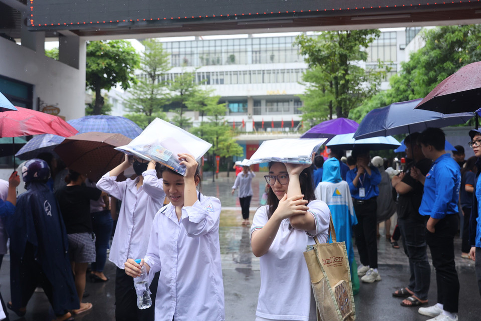 Thí sinh đội mưa rời khỏi phòng thi với tâm trạng phấn khởi. (Ảnh: PV/Vietnam+)