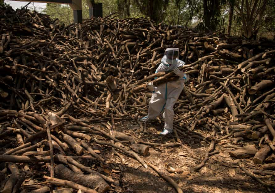 Một người mặc đồ bảo hộ đi lấy củi để hỏa thiêu bệnh nhân COVID-19 (Nguồn: Guardian)