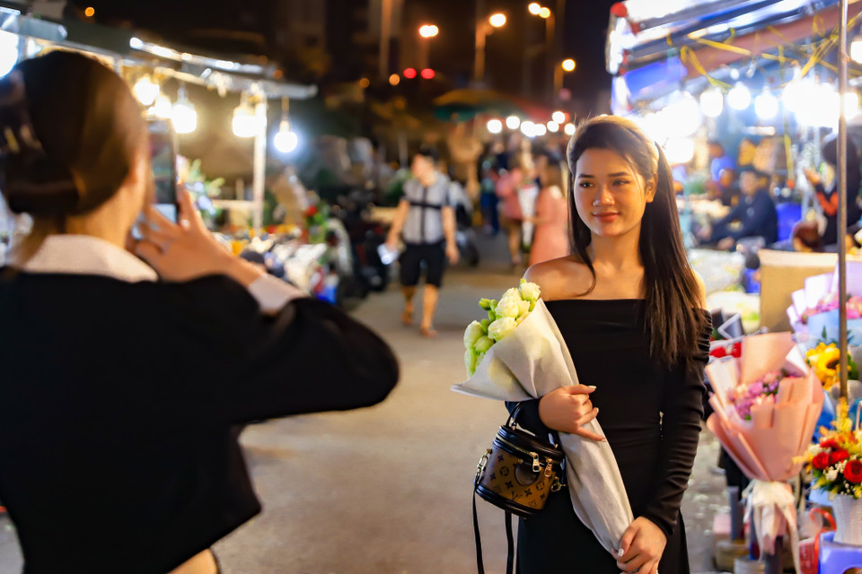 Nhiều bạn trẻ tranh thủ ghi lại những bức ảnh kỷ niệm giữa ‘rừng hoa.’ Thảo và Tuyết lần đầu tới chợ hoa Quảng An và cảm thấy rất hào hứng khi ở đây có đa dạng loại hoa đẹp. (Ảnh: Hoài Nam/Vietnam+)