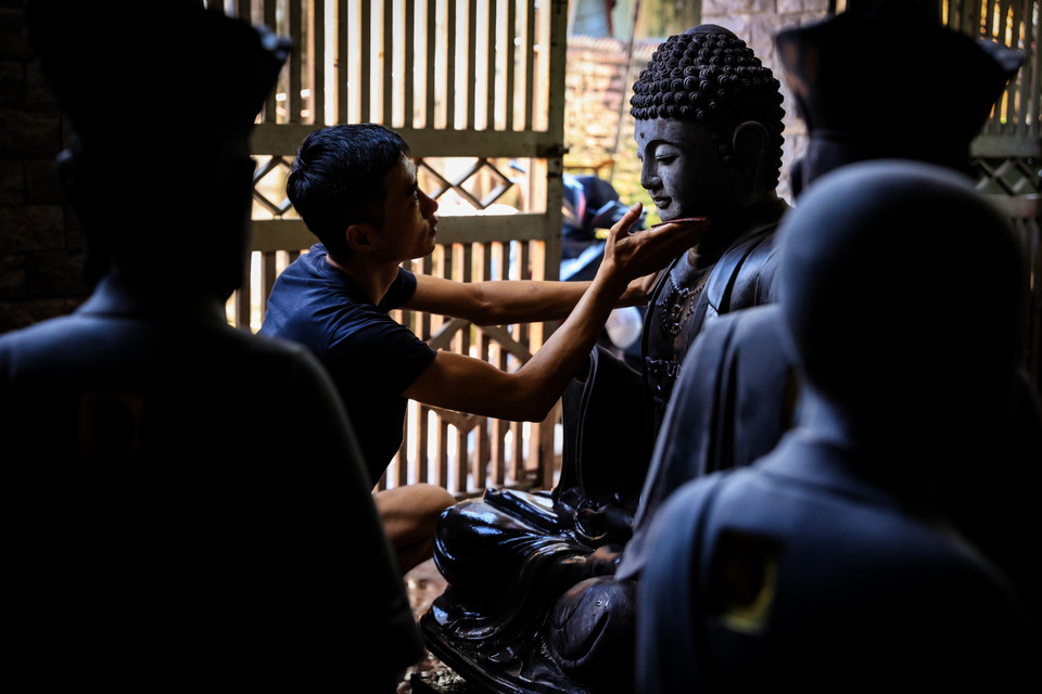 Đôi mắt đau đáu với nghề và đôi bàn tay tỉ mỉ vẫn luôn hằng ngày miệt mài bên những thớ gỗ mùi sơn với những sản phẩm tượng Phật. (Ảnh: Hoài Nam/Vietnam+)