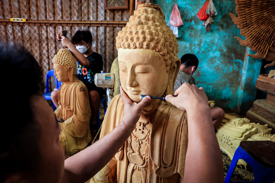 Sau nhiều năm cần mẫn nghe cha 'cầm tay chỉ việc,' hiện nay anh cũng đã có một xưởng riêng chế tác tượng phật bằng gỗ. (Ảnh: Hoài Nam/Vietnam+)