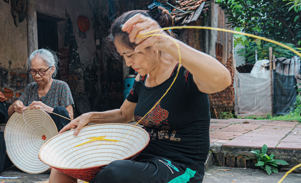 Trải qua bao thăng trầm của thời gian, mặc dù nghề làm nón không còn hưng thịnh như xưa, người dân làng Chuông vẫn miệt mài khâu từng chiếc nón. (Ảnh: Hoài Nam/Vietnam+)