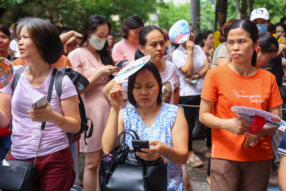 Phụ huynh căng thẳng chờ đợi bên ngoài điểm thi, nhiều người thấp thỏm liên tục xem giờ ngóng đợi con em. (Ảnh: PV/Vietnam+)