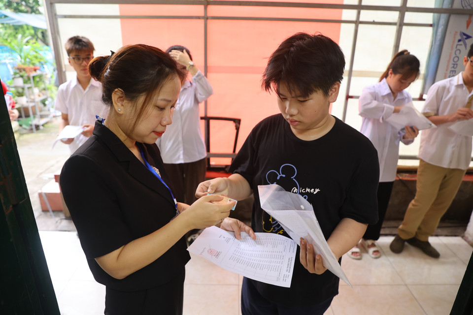 Cán bộ coi thi kiểm tra thông tin cá nhân của thí sinh trước khi bước vào môn thi đầu tiên. (Ảnh: PV/Vietnam+)