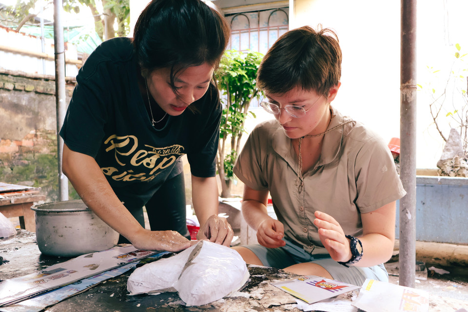 Du khách người Pháp trải nghiệm một công đoạn làm mặt nạ giấy bồi. (Ảnh: Hoài Nam/Vietnam+)