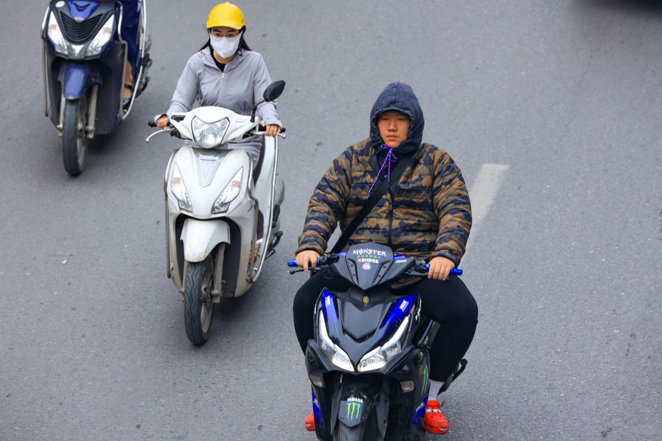 Người điều khiển xe máy trên đường cảm nhận rõ không khí lạnh vào sáng sớm nay. (Ảnh: Hoài Nam/Vietnam+)