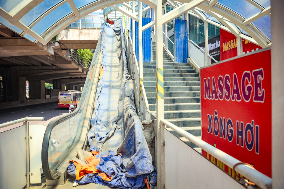 Điểm ga Phú Diễn thang máy vẫn phủ bụi cùng những biển vẫy của hàng quán xung quanh. (Ảnh: Hoài Nam/Vietnam+)