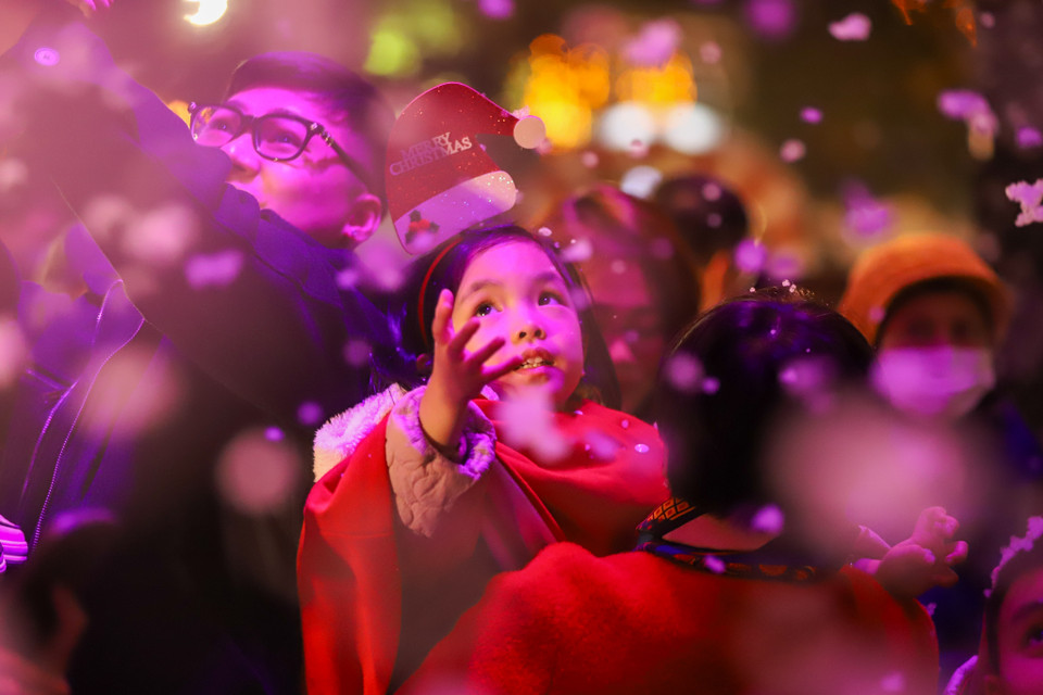 Nhiều bạn nhỏ rất thích thú với trải nghiệm này. Không khí lạnh giá tại Hà Nội thời điểm này cùng với "cơn mưa tuyết" tạo nên một Giáng sinh như ở trời Tây. (Ảnh: Hoài Nam/Vietnam+)