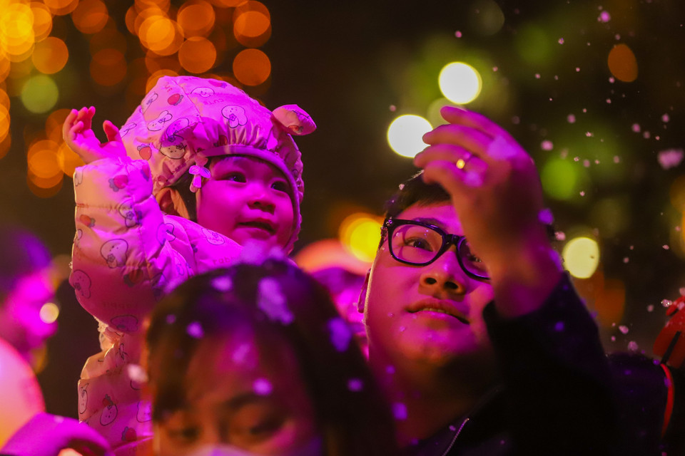 Gia đình đưa các em nhỏ đi chơi tại phố đi bộ Trần Nhân Tông. Người dân thích thú với những bông tuyết trắng rơi nhẹ nhàng, lãng mạn... (Ảnh: Hoài Nam/Vietnam+)