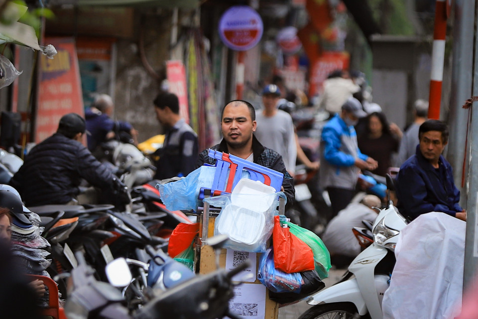Xe hàng nước vẫn len lỏi giữa rừng xe máy đỗ trên vỉa hè, tìm kiếm một không gian đỡ ngột ngạt hơn để bày bán. (Ảnh: Hoài Nam/Vietnam+)