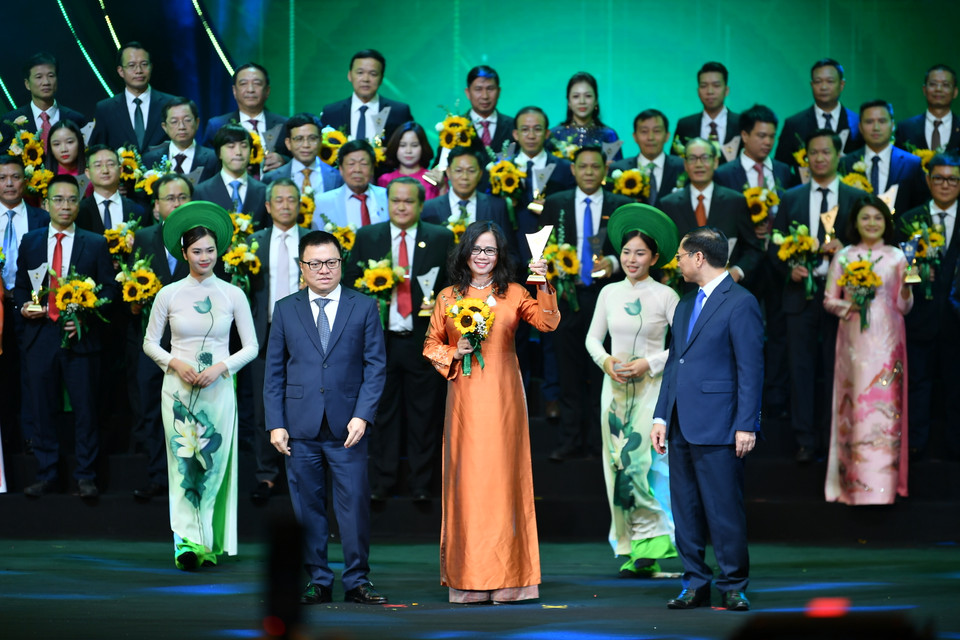 Phó Thủ tướng Chính phủ, Bộ trưởng Ngoại giao Bùi Thanh Sơn và Tổng Biên tập Báo Nhân Dân, Chủ tịch Hội Nhà báo Việt Nam Lê Quốc Minh trao biểu trưng và hoa cho đại diện các doanh nghiệp. (Ảnh: Hoài Nam/Vietnam+)