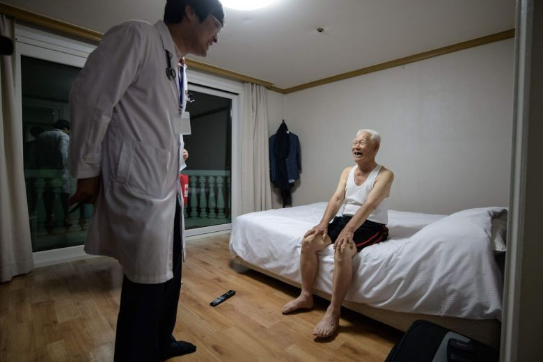 Một nhân viên y tế kiểm tra sức khỏe cho cụ ông tham gia sự kiện đoàn tụ gia đình ly tán trong Chiến tranh Triều Tiên.