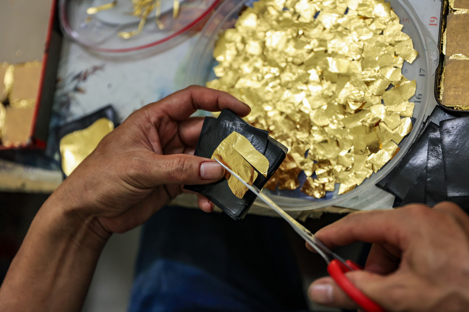 Cắt dòng lá vàng, một trong những công đoạn của khâu cán vàng, bạc. (Ảnh: Hoài Nam/Vietnam+)