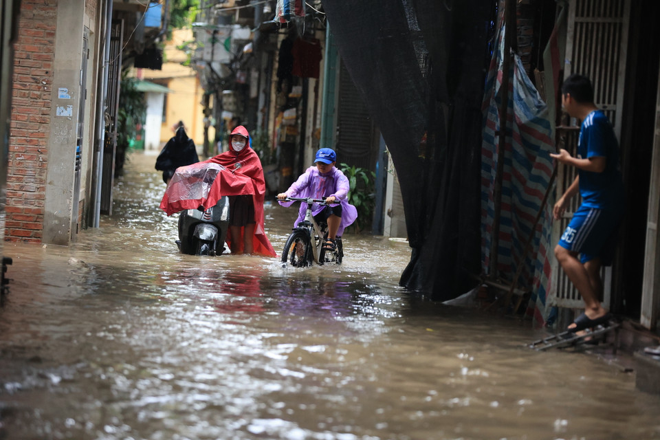 Việc di chuyển đi học đi làm của người dân gặp nhiều khó khăn qua những đoạn nước ngập sâu. (Ảnh: Hoài Nam/Vietnam+)