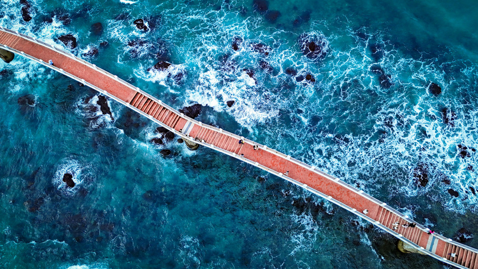 Cây cầu bắc qua đảo khi nhìn từ trên cao nổi bật giữa làn nước xanh dịu mát của biển cả. (Ảnh: Hoài Nam/Vietnam+)