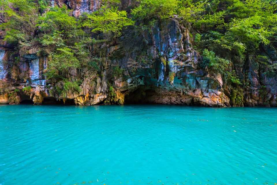 Hầu hết thời gian trong năm, nước sông Nho Quế có màu xanh ngọc lục bảo tuyệt đẹp, ánh lên giữa những chân núi đá xám lạnh, bên cạnh những mảng xanh thẫm trong không gian hùng vĩ của rừng già, đá núi và mây trời. (Ảnh: Hoài Nam/Vietnam+)