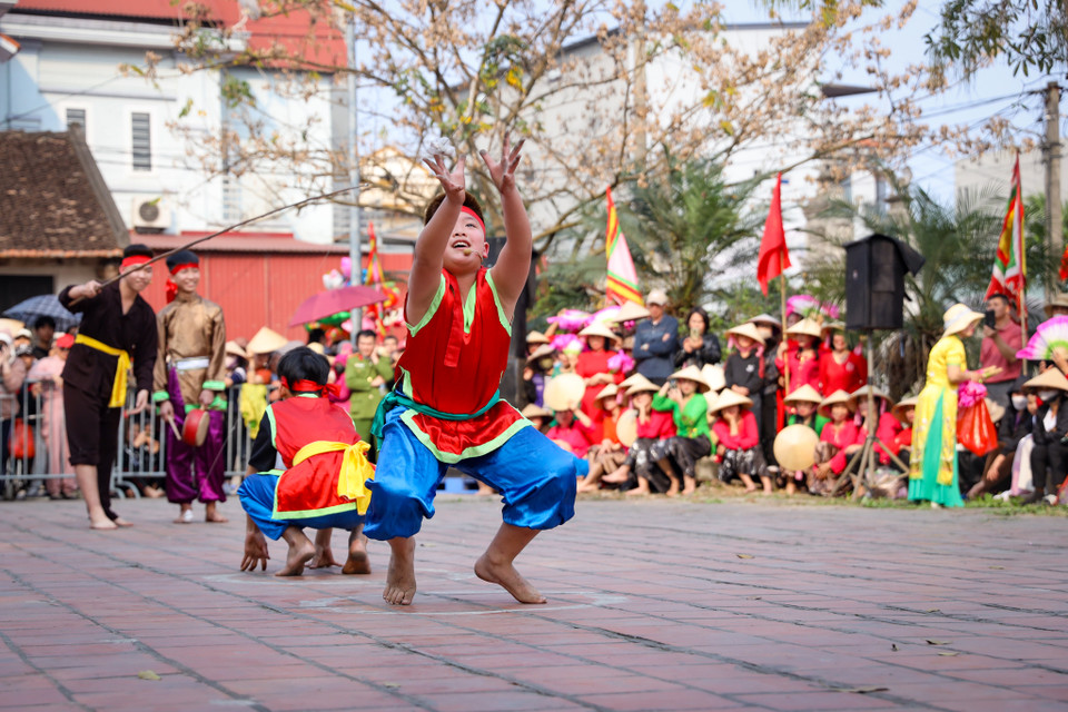 Những ‘chú ếch’ cũng phải kết hợp với chàng rể, diễn sao cho có tư thế giống con ếch nhất và về đích nhanh nhất. (Ảnh: Hoài Nam/Vietnam+)