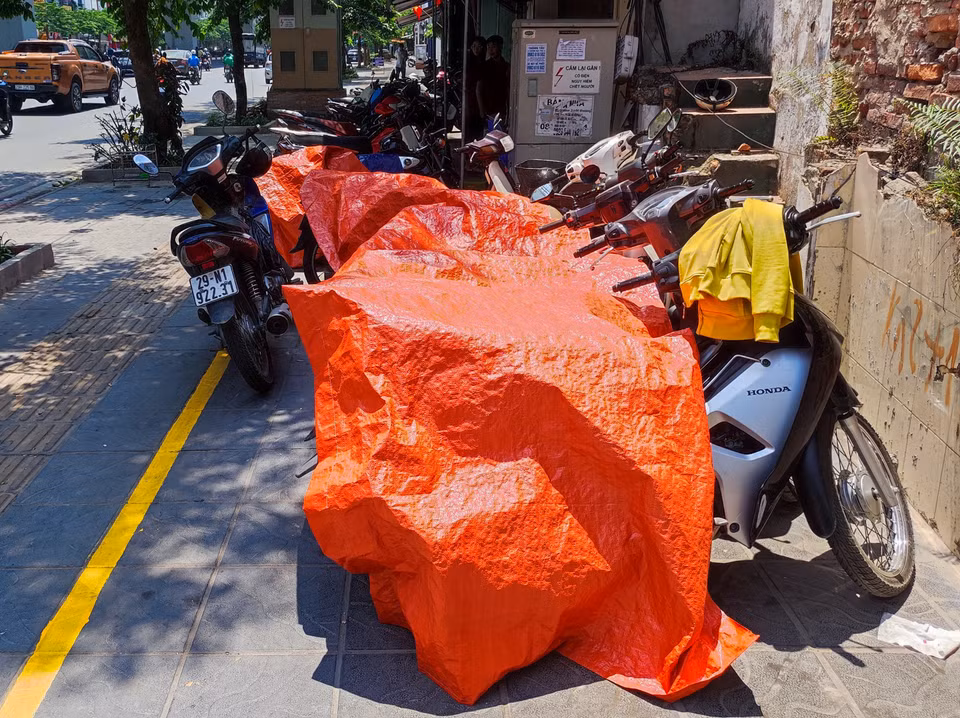 Người dân dùng bạt để che phủ phương tiện dưới thời thiết nắng nóng gay gắt. (Ảnh: Hoài Nam/Vietnam+)
