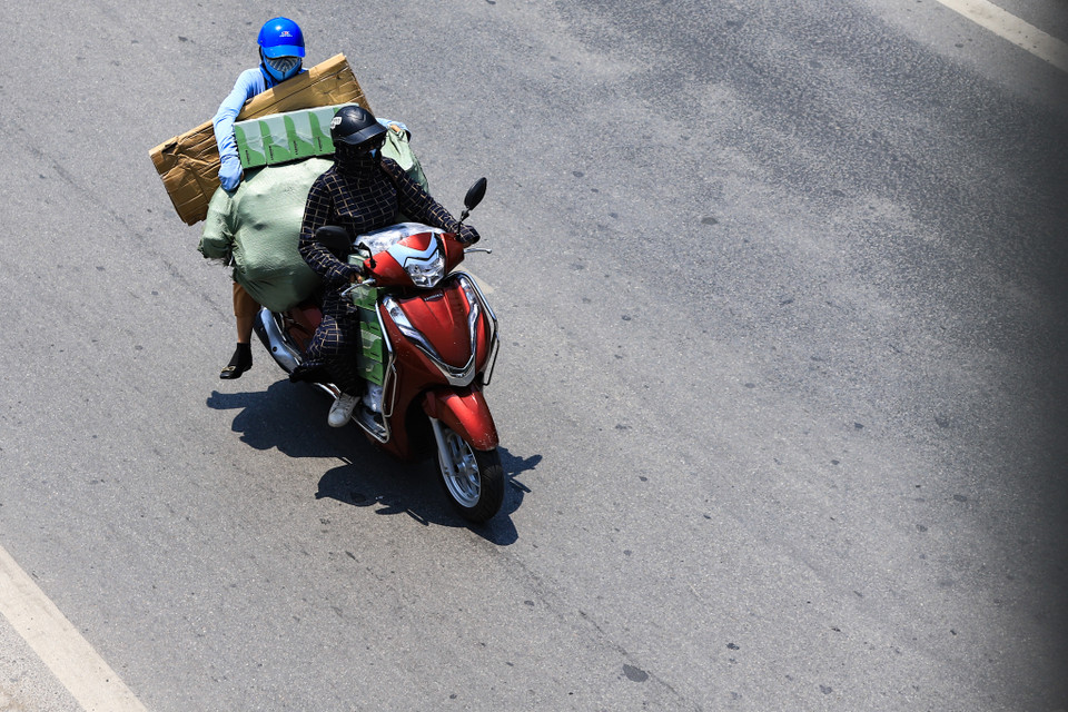 Tuy nhiên, vì đặc thù công việc nên một số người dân vẫn phải di chuyển trên mặt đường như chảo lửa giữa buổi trưa. (Ảnh: Hoài Nam/Vietnam+)