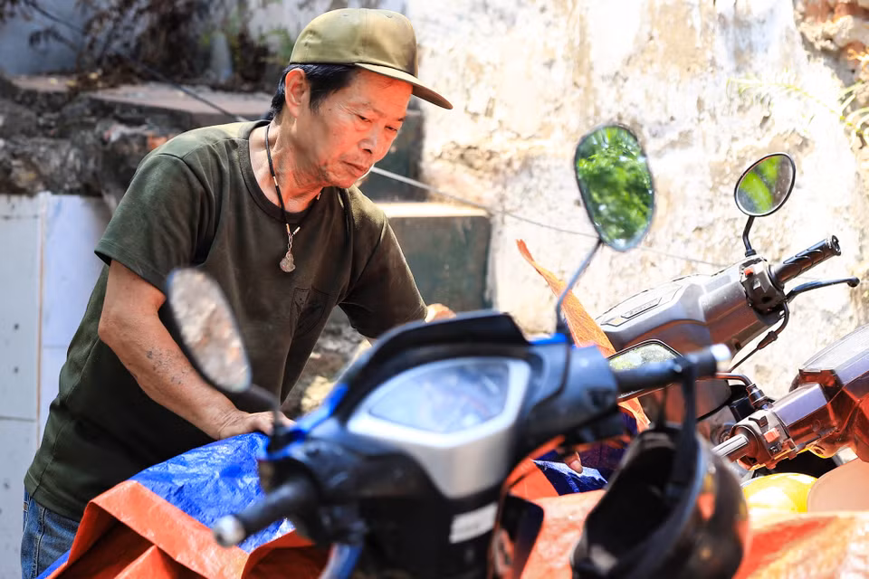 Anh Hùng trông coi xe tại một quán ăn trên đường Đại La thường xuyên phải làm việc vào khoảng thời gian 11 giờ đến 13 giờ chia sẻ: ‘Thời tiết nắng nóng rất khó chịu, mặc dù ngồi dưới bóng cây nhưng hơi nóng dưới mặt đường bốc lên rất ngột ngạt.’ (Ảnh: Hoài Nam/Vietnam+)