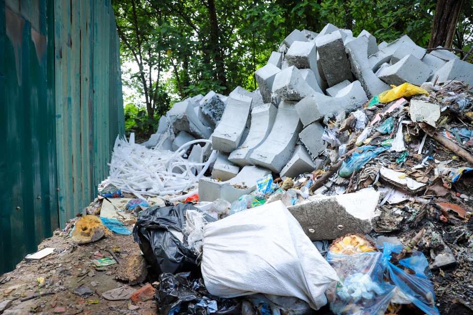 Một phần diện tích của con ngõ nằm trong dự án xây dựng trường học, những đoạn thuộc dự án đã có rào tôn tuy nhiên ngay bên cạnh là đủ loại rác thải đổ trộm. (Ảnh: Hoài Nam/Vietnam+)