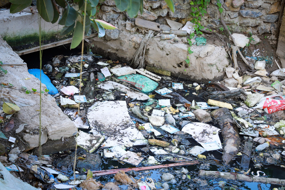 Khu vực cống bị rác lấp kín, ùn ứ làm cho dòng nước đen ngòm không thể lưu thông. (Ảnh: Hoài Nam/Vietnam+)