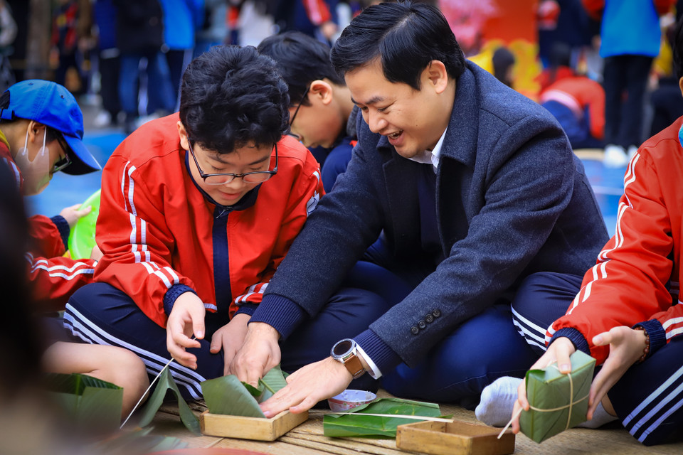 Thầy giáo Lưu Văn Thông- Hiệu trưởng trường trung học cở sở Dịch Vọng hướng dẫn học sinh gói bánh chưng và chia sẻ về phong tục gói bánh chưng ngày Tết của dân tộc. (Ảnh: Hoài Nam/Vietnam+)