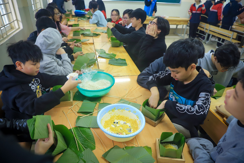 Tại trường Trung học cơ sở Dịch Vọng (Cầu Giấy, Hà Nội), các học sinh rất hào hứng và chăm chú khi được trải nghiệm tự tay mình gói những chiếc bánh chưng cho ngày Tết. (Ảnh: Hoài Nam/Vietnam+)