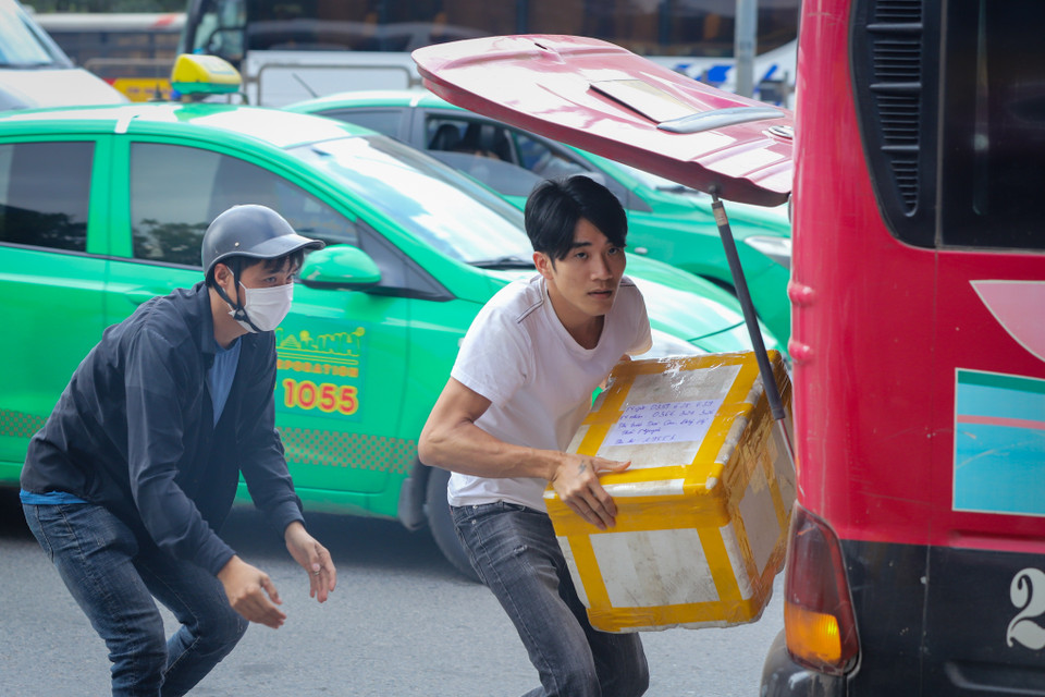 Một xe khách dừng giữa đường, ‘chật vật’ nhận chở thêm hàng hóa vì vắng khách. (Ảnh: Hoài Nam/Vietnam+)