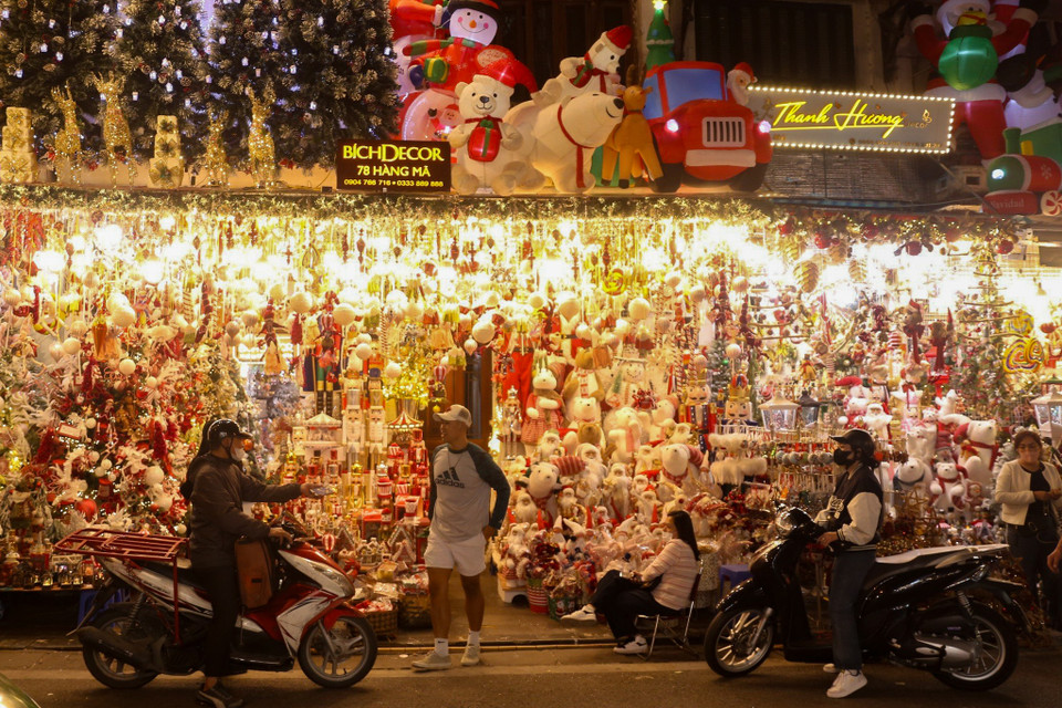 Các đồ trang trí quen thuộc cho đêm Giáng sinh như cây thông, trang phục Noel, vòng hoa, chữ trang trí… được tiểu thương treo bán trước cửa hàng. (Ảnh: PV/Vietnam+)