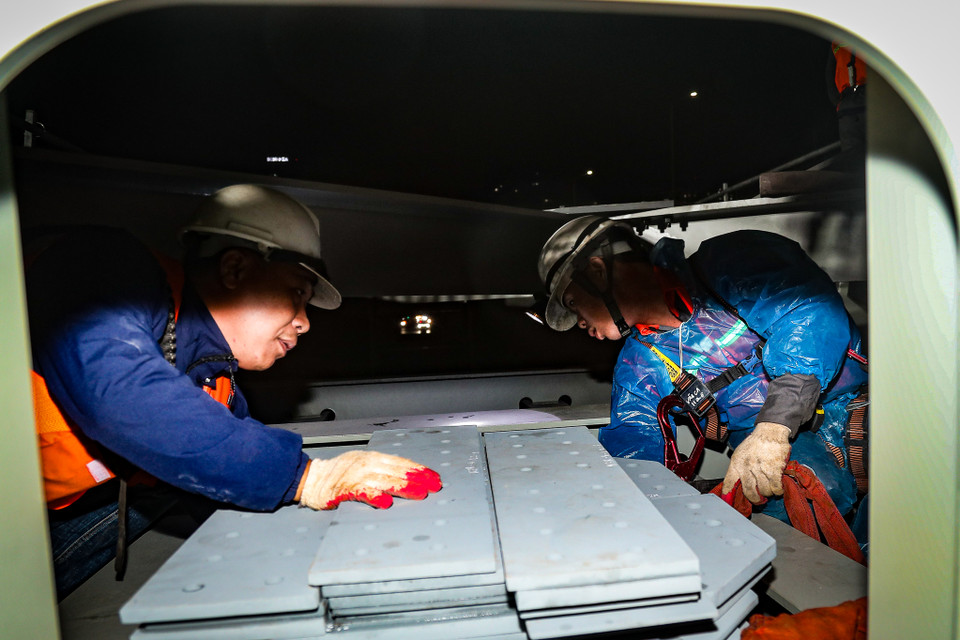 Thi công trong đêm giá rét các công nhân phải mặc thêm áo mưa để giữ ấm. (Ảnh: Hoài Nam/Vietnam+)